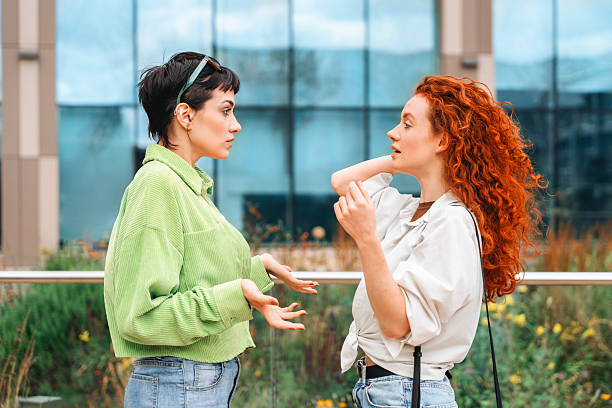 istock Two friends engage in a lively conversation outdoors near a modern building during the day, showcasing friendship and casual attire 2224128235