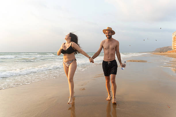 istock Happy couple walking on the beach at sunset holding hands 2224131530