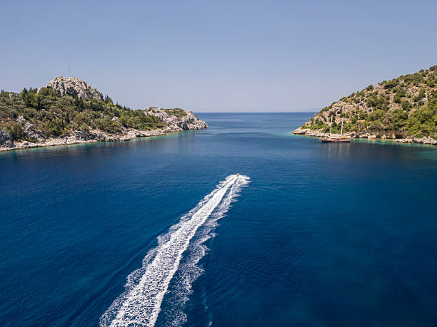La Spezia, Italy - July 23, 2022: White motorized dinghy with three people on board (a man and two women), in motion on a sunny summer day in the Mediterranean sea, Gulf of La Spezia or Gulf of Poets, Liguria, Italy, southern Europe.