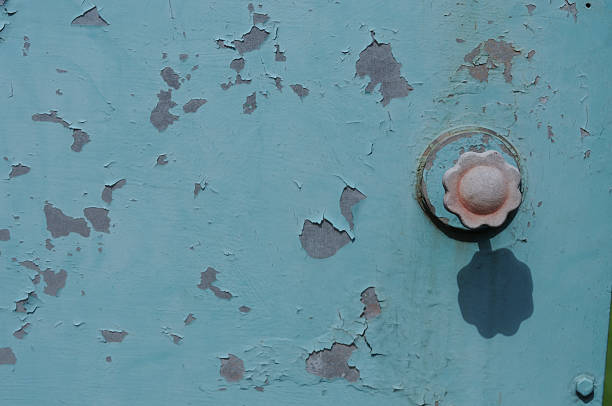 Old peeling paint on a blue metal door with a rusty screw