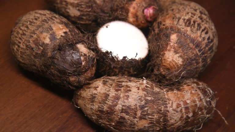 Yam on a rustic wooden background. In portuguese: Inhame. Video with rotating movement.