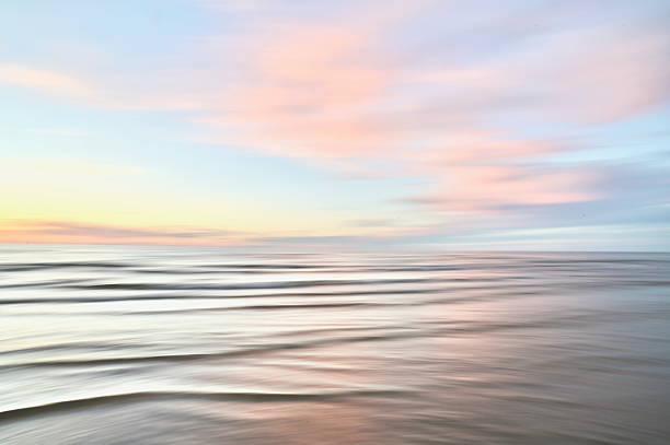 A dreamy, impressionistic paint like blurred sea sunset background with gently soft pastel colours.