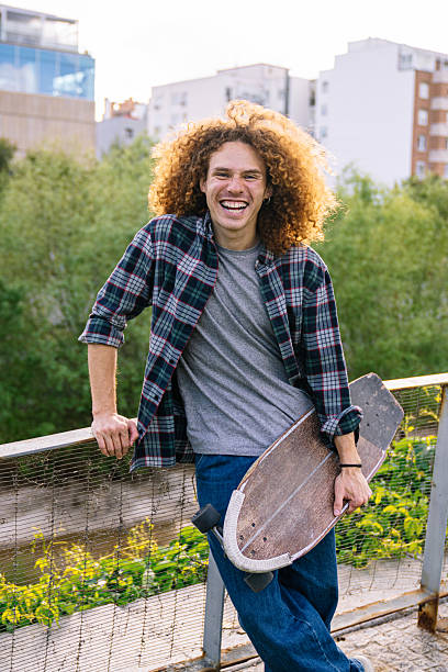 istock Young skater holding his longboard and smiling at camera 2224148278