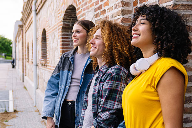istock Young people leaning against a brick wall, enjoying a sunny afternoon together 2224149046