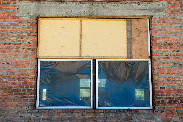 istock Boarded up windows with plastic sheeting reveal exposed brick at a construction site during daylight hours 2224152285