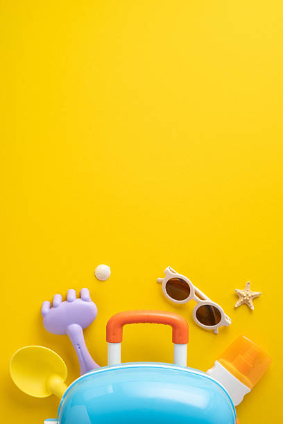istock Bright vertical yellow background featuring travel accessories such as a blue suitcase, sunglasses, and beach toys. Perfect for summer, vacation, and travel concepts 2224158444