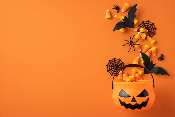 istock Festive orange pumpkin bucket filled with candy corn and Halloween elements such as bats and spiders 2224158501