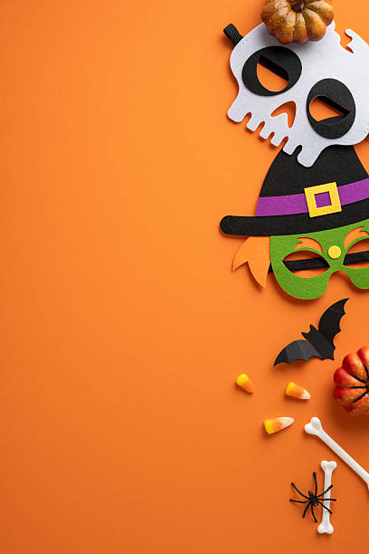 istock Halloween-themed vertical arrangement featuring masks, candy corn, a bat, and a pumpkin on a bright orange background conveying festive holiday vibes and spooky decorations 2224158502