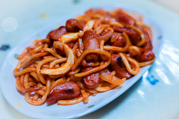 Stock photo showing close-up view of  a delicious chicken chow mein noodle stir fry meal, sizzling in a frying pan. This Chinese food classic is made with tender chicken pieces stir-fried with fresh vegetables and savoury noodles, all coated in a rich, flavourful sauce.
