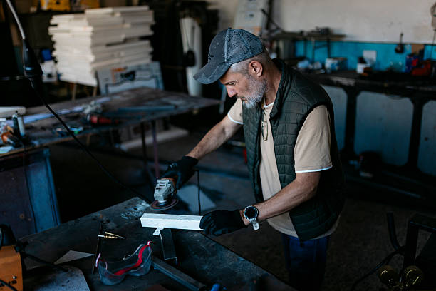istock Metalworker smoothing metal bar with electric sander in workshop 2224164138