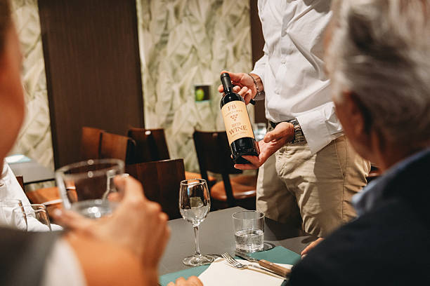 istock Waiter showing red wine bottle to customers in restaurant 2224164432