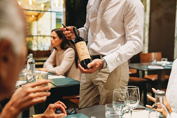 istock Waiter showing red wine bottle to customers in restaurant 2224164448