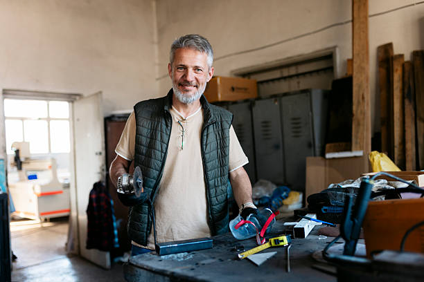 istock Metalworker smiling at the camera holding an angle grinder in his workshop 2224164523