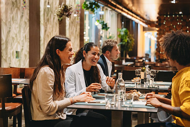 Cheerful businesswomen laughing while having dinner together at restaurant