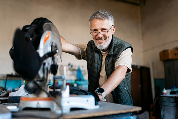 istock Senior carpenter smiling and using a miter saw in his workshop 2224165019