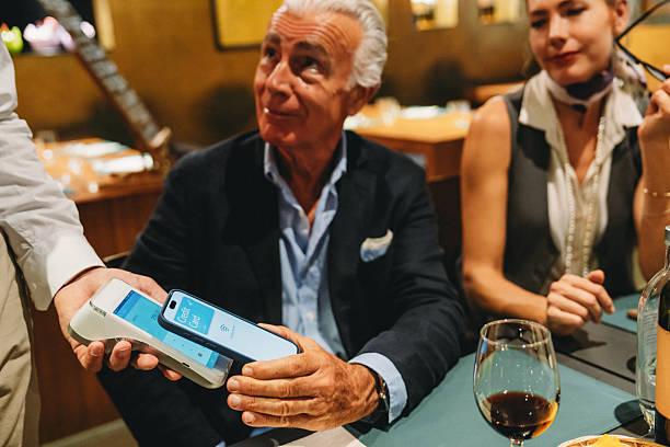 istock Elegant mature man paying with smartphone in restaurant 2224165109
