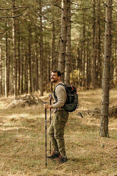 istock Smiling hiker exploring forest trail with hiking poles and backpack 2224174882