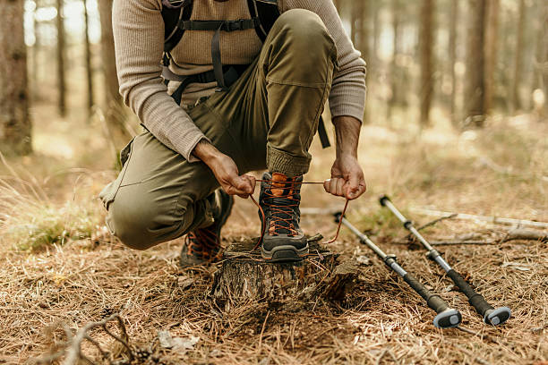 Hiker tying his boots in the forest during a trekking day