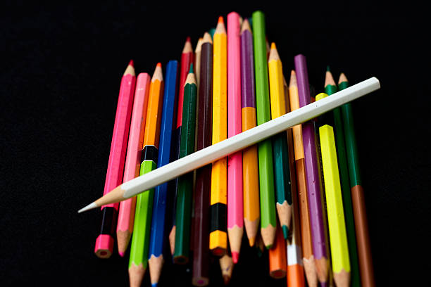 A variety of colored pencils are stacked in an artistic manner, featuring bright hues against a dark background, showcasing an inviting atmosphere for creativity.
