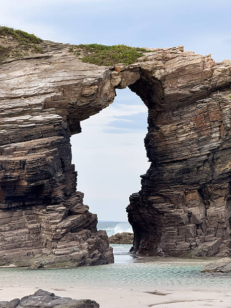 istock Rock arch formation on white sand beach in northern Spain 2224183492