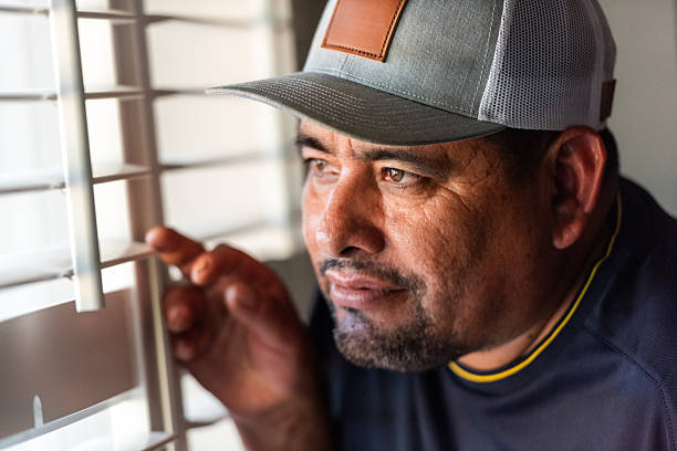 Serious, worried, stressed hispanic mature man looking through a window