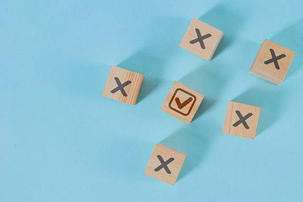 istock Five wooden blocks on a blue background, with one block with a check mark standing out from the others with an X. 2224189017
