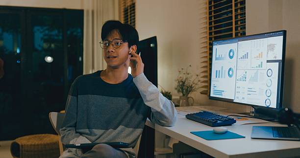 istock Young Asian man financial advisor working late at home, using tablet and laptop, discussing strategy with clients via video call, showcasing remote work efficiency. Remotely and finance. 2224192365