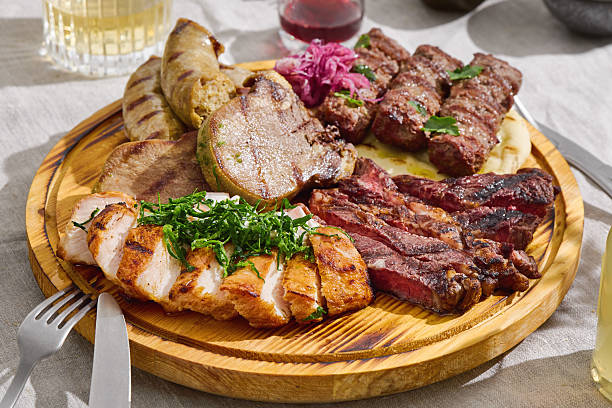 Grilled meat assortment platter in bright natural light overhead, rustic wooden board presentation.