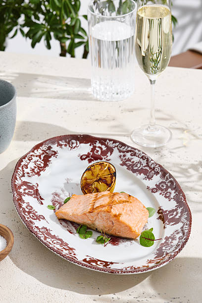 istock Grilled salmon steak with charred lemon, bright daylight, overhead composition on vintage-patterned plate 2224193904