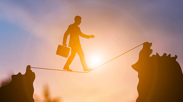 istock Businessman Walking on a Tightrope at Sunset 2224195036