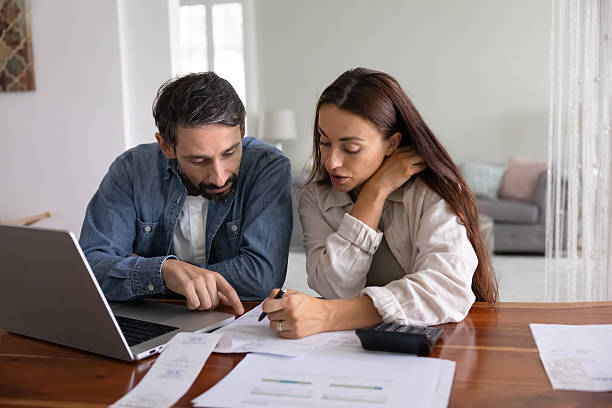 Serious young middle aged couple analyzing personal domestic budget