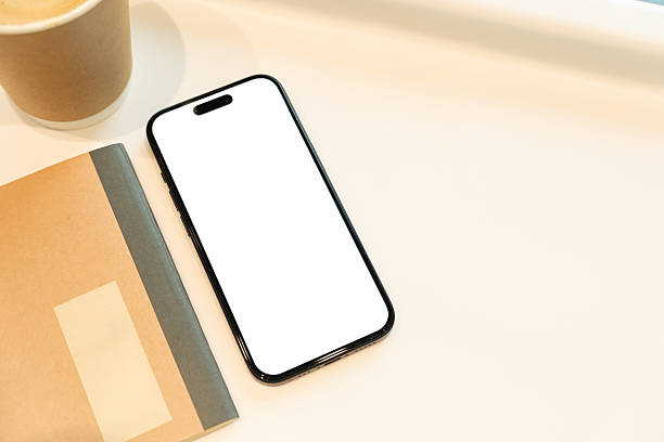 istock Office Desk with Blank Smartphone, Notebook, and Coffee. Copy space. The composition suggests a workspace ready for digital content or an app interface to be showcased. 2224197721