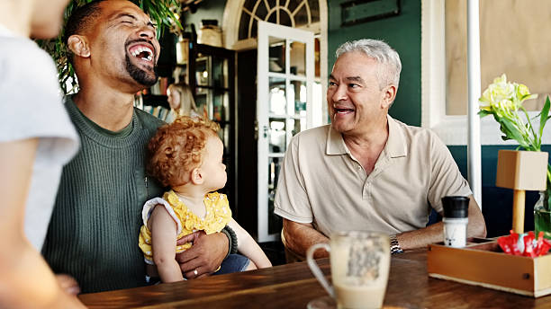 Multi-generational family enjoying time together in a cafe while the parent holds a cute little girl with curly hair and laughs
