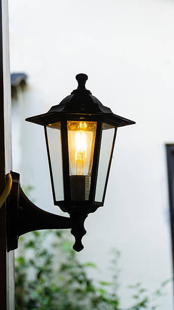 istock A dark wall-mounted lantern, emitting a bright, warm light against a light background 2224201024