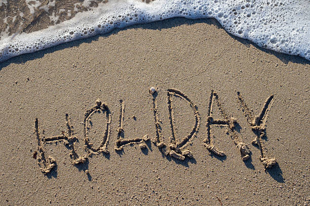 istock Soft wave washing away holiday writing on the beach sand 2224201146