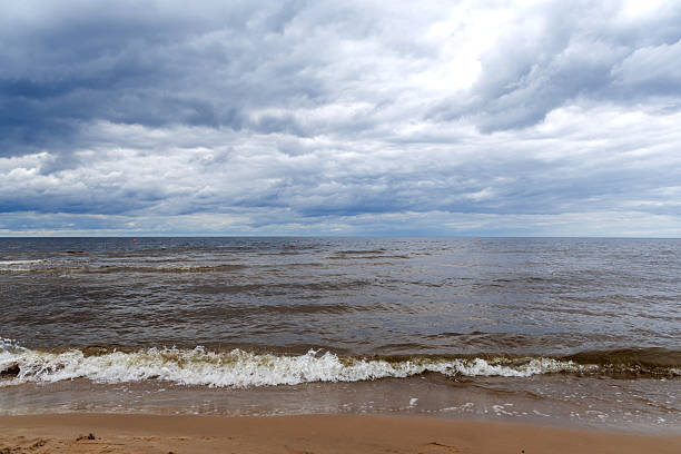 istock .A gloomy, cloudy day by the sea, where waves crash on a sandy shore 2224203239