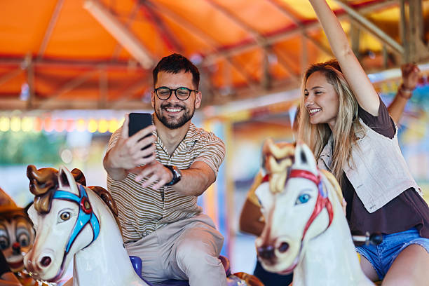istock Happy couple taking a selfie during carousel ride at amusement park. 2224204545