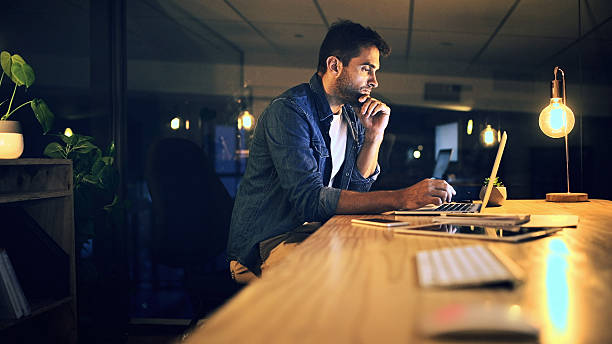 istock Laptop, night and thinking with business man in office for deadline or feedback on creative report. Computer, problem solving and research with design employee at work for productivity in overtime 2224204966