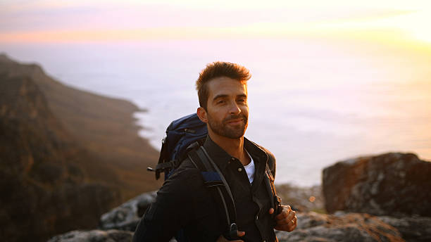 istock Hiking, backpack and man with portrait on mountain for trekking adventure, break or explore nature. Sunrise, smile and person with ocean view for travel, backpacker journey and relax at destination 2224209580