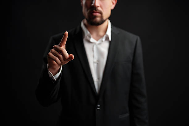 istock Businessman gestures with pointer finger in a serious demeanor against dark background during professional setting 2224210008