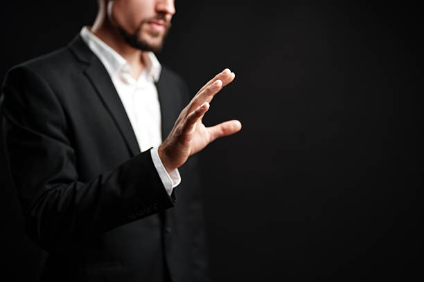 istock Professional man gesturing with hand against dark background in a corporate setting during afternoon hours 2224210211