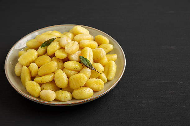 Homemade Easy Potato Gnocchi on a Plate on a black background, side view. Copy space.