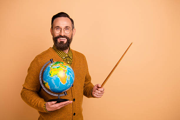 Photo of positive mature man teacher hold globe point pointer empty space wear pullover sweater isolated over beige color background