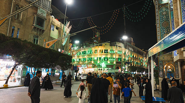 Karbala, Iraq - March 17, 2025: Visitors walk through the vibrant streets of Karbala at night, enjoying cultural activities and festive decorations.