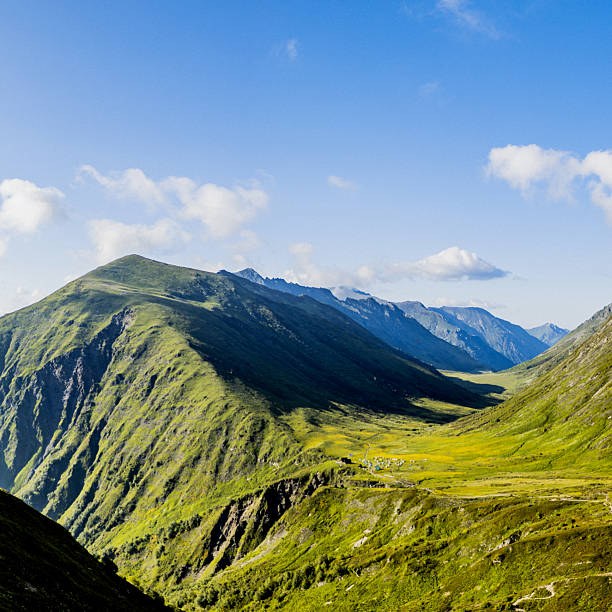 Beautiful mountain valley stretching into the distance, surrounded by verdant hills and a vibrant sky.