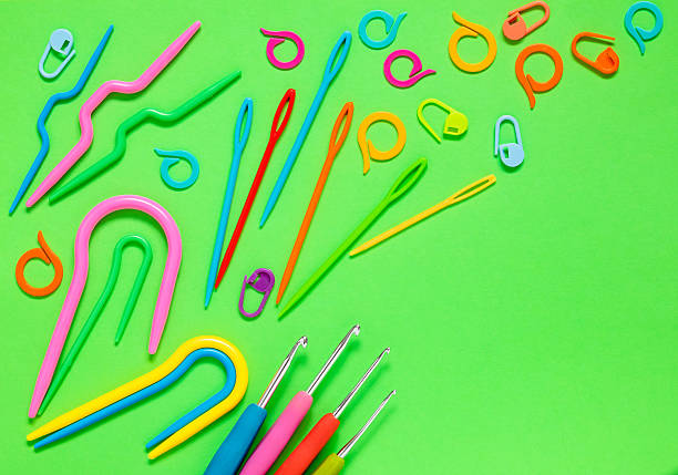 Knitting tools on a green background. Crochet hooks, plastic knitting nedles, markers, curved needles. Flat lay. Copy space.