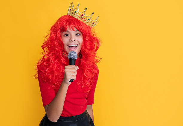 istock positive kid in crown with microphone on yellow background 2224221761