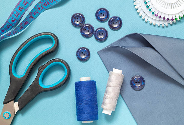 istock Sewing tools for tailoring on a blue background. Fabric, scissors, buttons, centimeter, pins, needle, threads spool. Flat lay. Top view. 2224222414