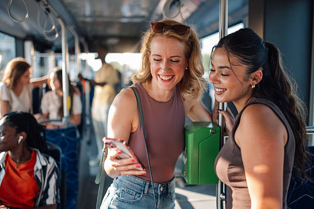 istock Two young women sharing a laugh while looking at a smartphone on the bus 2224225498