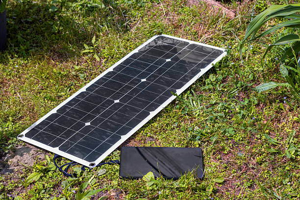 istock Portable solar panel charging a device on grass, illustrating renewable energy use in nature. for showcasing green technology and sustainable practices 2224225654